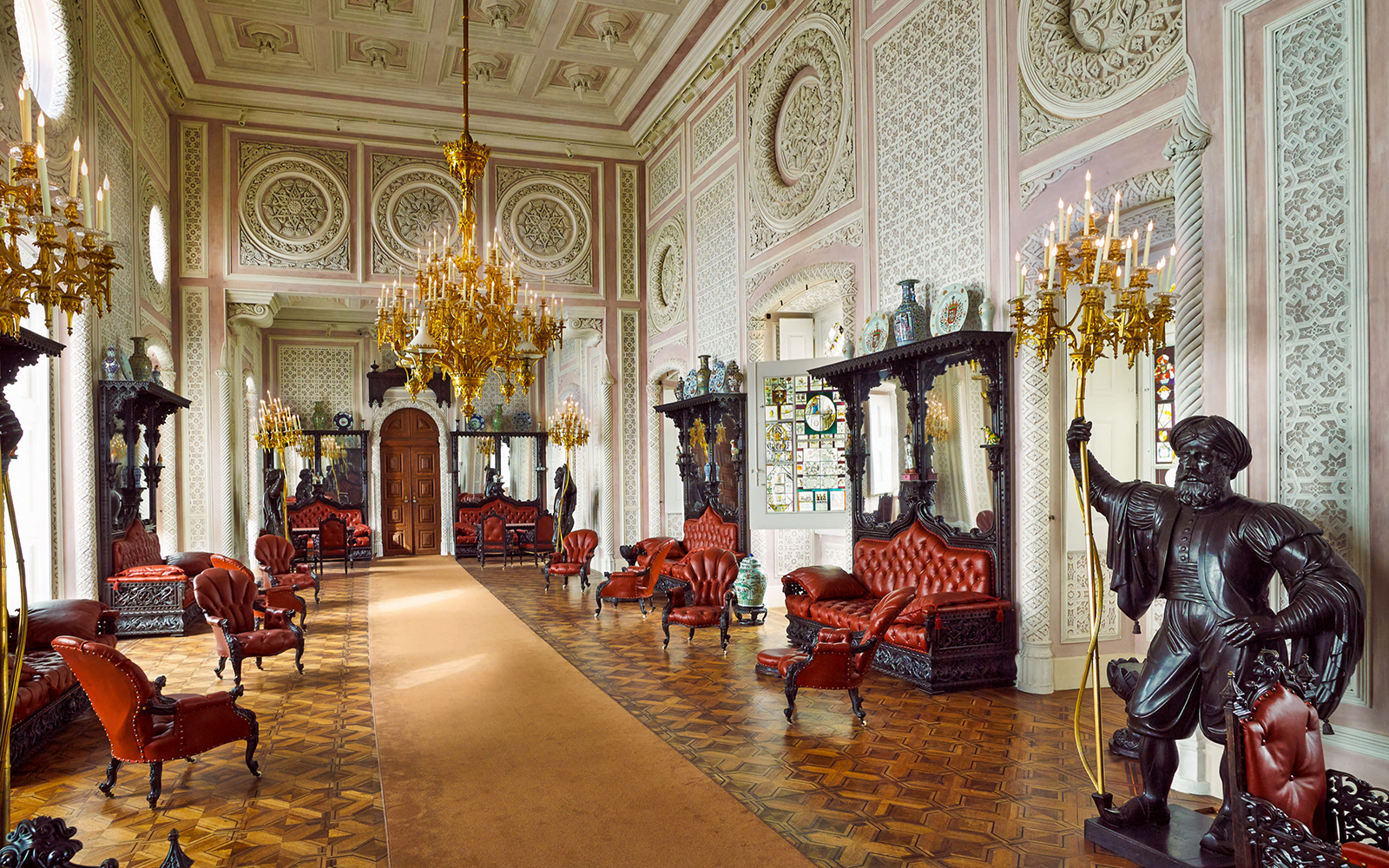 Luxurious interior of Quinta da Regaleira with ornate chandeliers and red leather seating, Sintra, Portugal.