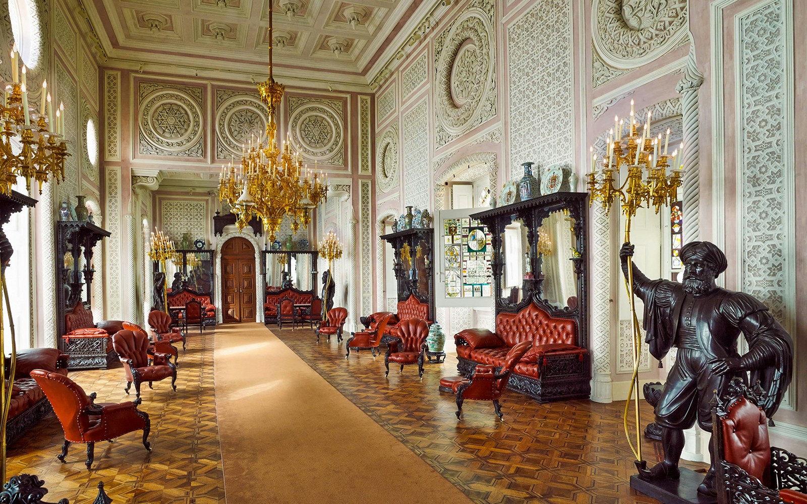 Luxurious interior of Quinta da Regaleira with ornate chandeliers and red leather seating, Sintra, Portugal.
