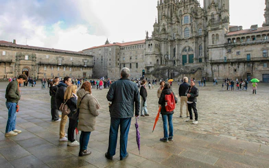Group of tourists on a guided tour outside Santiago de Compostela Cathedral, Spain.