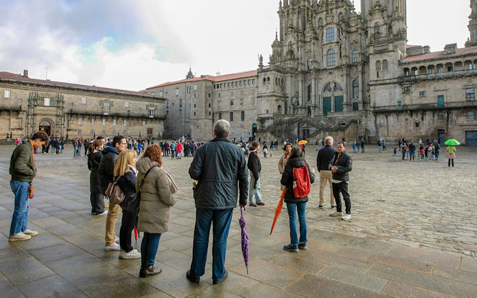 Group of tourists on a guided tour outside Santiago de Compostela Cathedral, Spain.