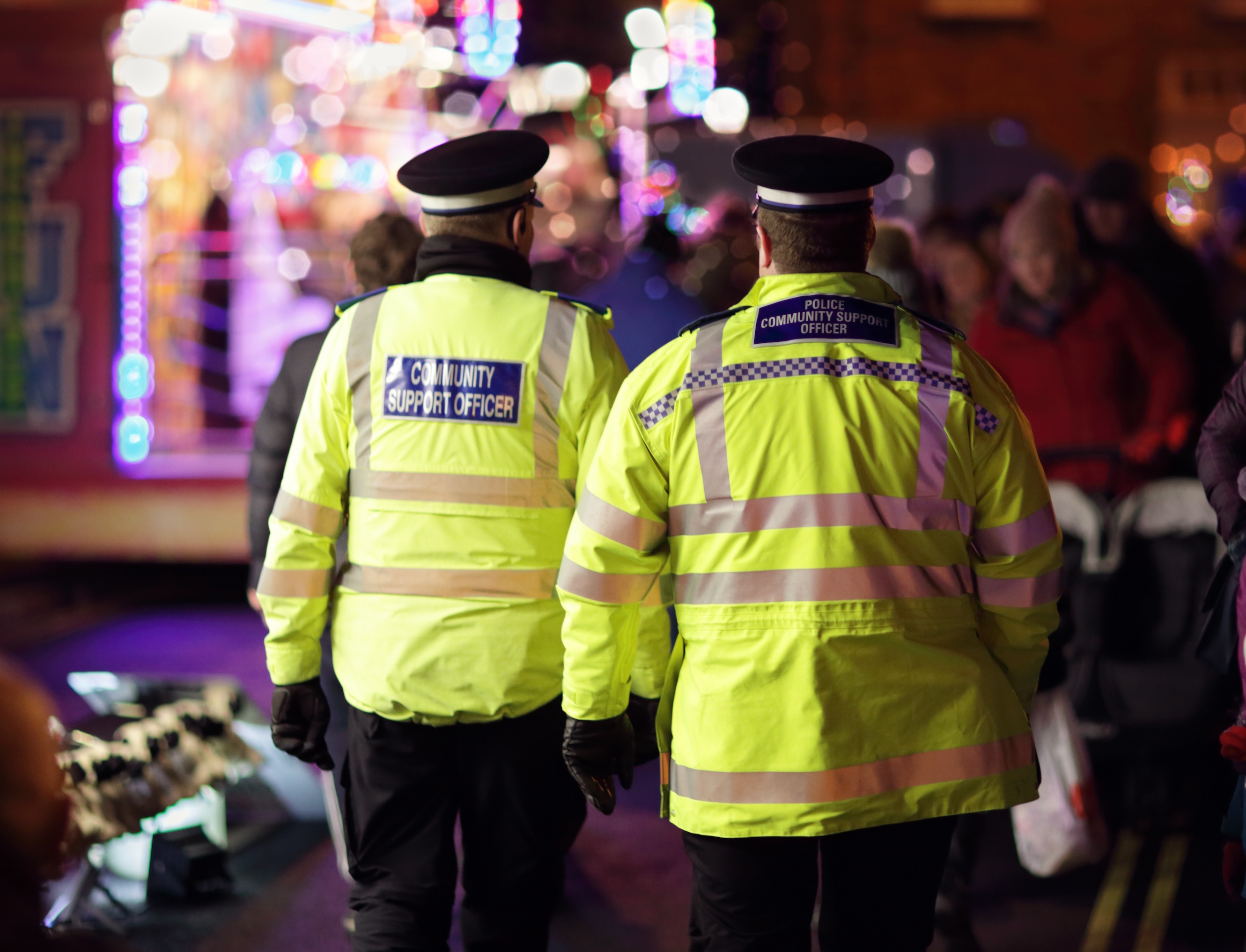 British police community support officers at a nighttime public event.