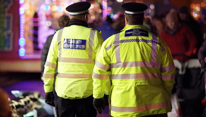 British police community support officers at a nighttime public event.