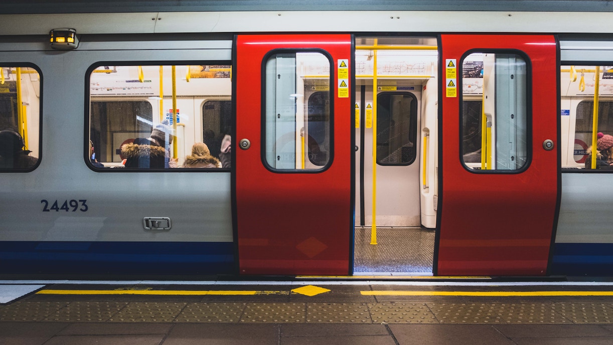 Metro train with open doors at a station platform, passengers seated inside.