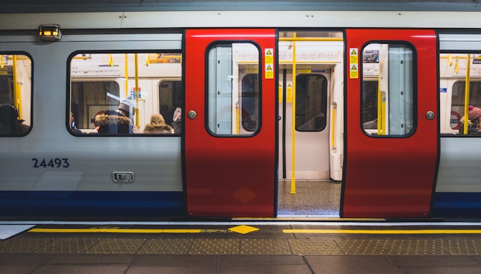 Metro train with open doors at a station platform, passengers seated inside.