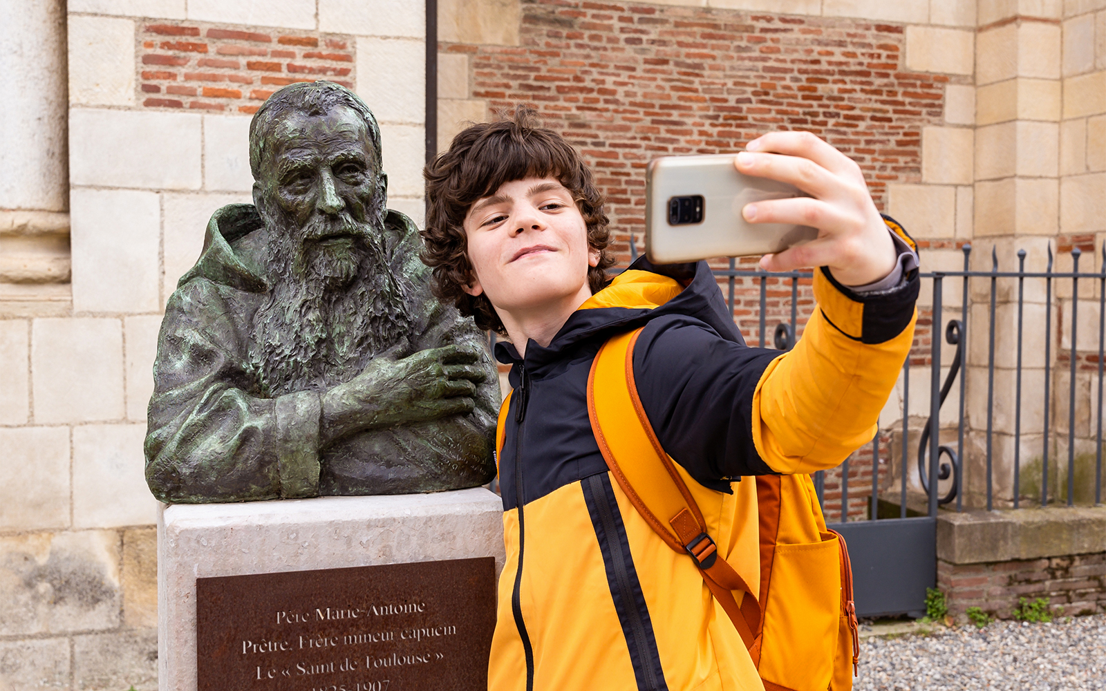 Teenager boy taking a selfie with a bust up statue