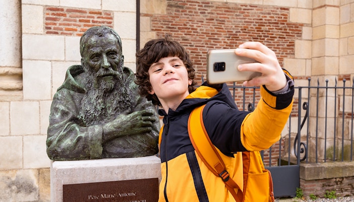 Teenager boy taking a selfie with a bust up statue