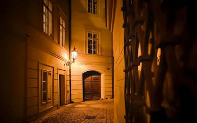 Narrow cobblestone alley in Old Town Prague illuminated by a street lamp.