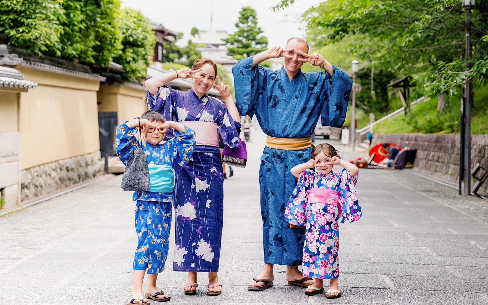 Family in traditional kimonos at Kyoto Kimono Rental Yumeyakata, posing playfully on a Kyoto street.