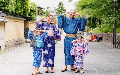 Family in traditional kimonos at Kyoto Kimono Rental Yumeyakata, posing playfully on a Kyoto street.