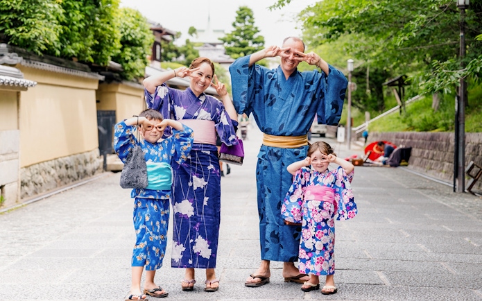 Family in traditional kimonos at Kyoto Kimono Rental Yumeyakata, posing playfully on a Kyoto street.
