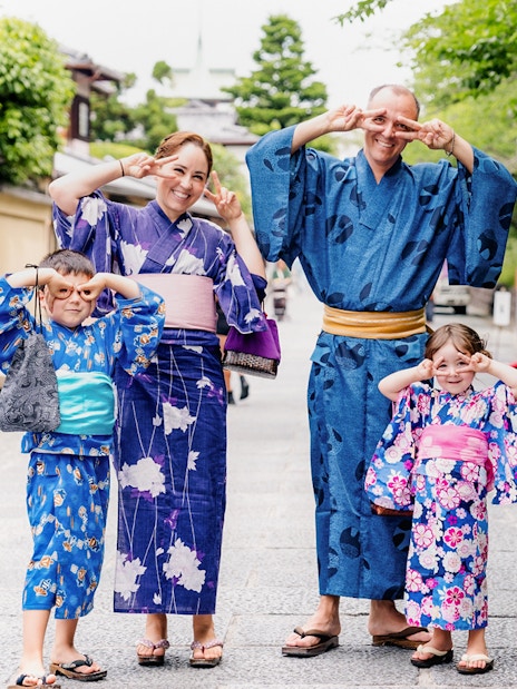 Family in traditional kimonos at Kyoto Kimono Rental Yumeyakata, posing playfully on a Kyoto street.