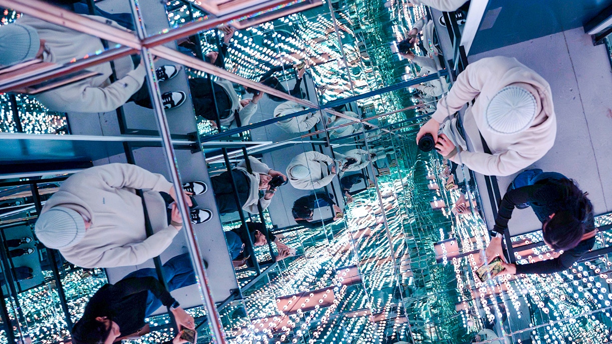 Guests exploring mirrored room at World Of Illusions with reflections and lights.