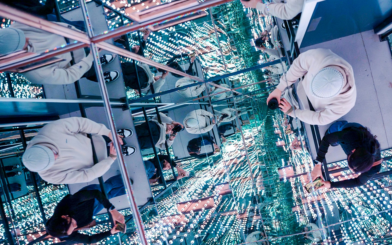 Guests exploring mirrored room at World Of Illusions with reflections and lights.