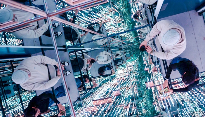 Guests exploring mirrored room at World Of Illusions with reflections and lights.