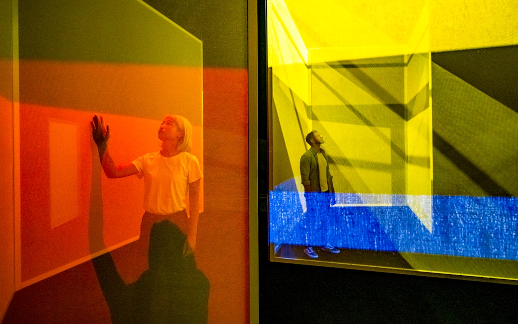 Visitors exploring colorful light installations at Frameless London exhibit.