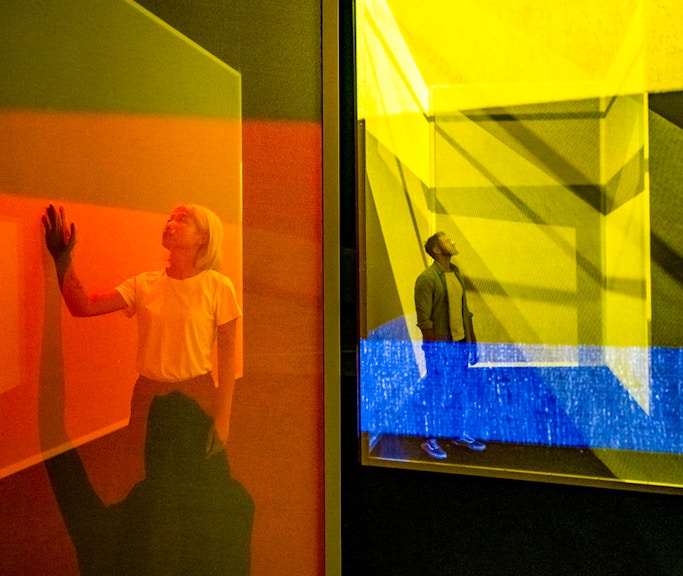 Visitors exploring colorful light installations at Frameless London exhibit.