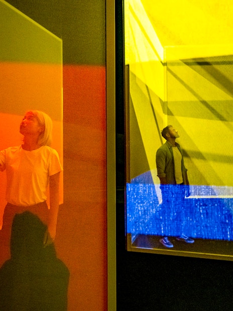 Visitors exploring colorful light installations at Frameless London exhibit.