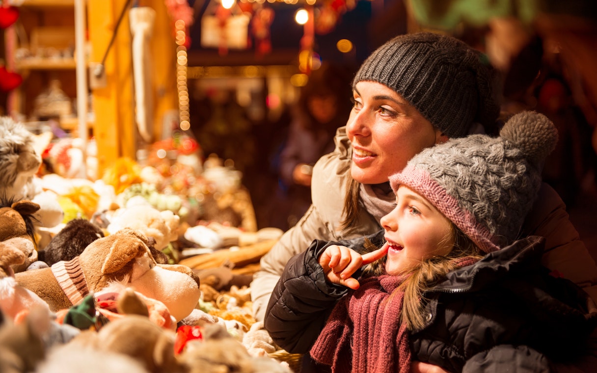Mother and child admiring toys at a Christmas market stall.