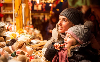 Mother and child admiring toys at a Christmas market stall.