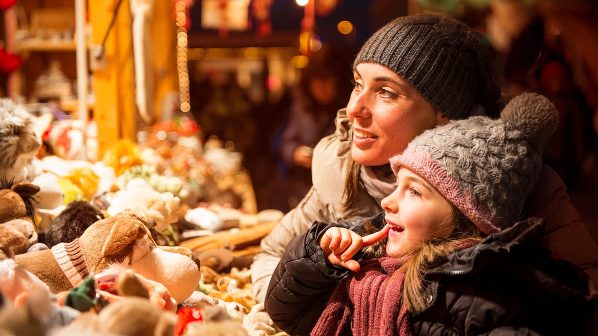 Mother and child admiring toys at a Christmas market stall.