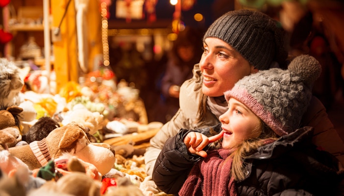 Mother and child admiring toys at a Christmas market stall.