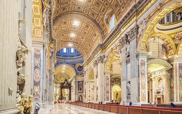 Interior of St. Peter's Basilica, showcasing ornate columns and detailed ceiling in Vatican City.