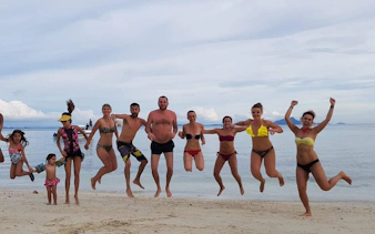 Small group jumping on Krabi beach during 4 Islands sunset speedboat tour.