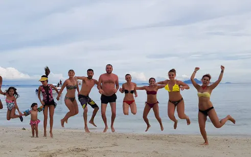 Small group jumping on Krabi beach during 4 Islands sunset speedboat tour.