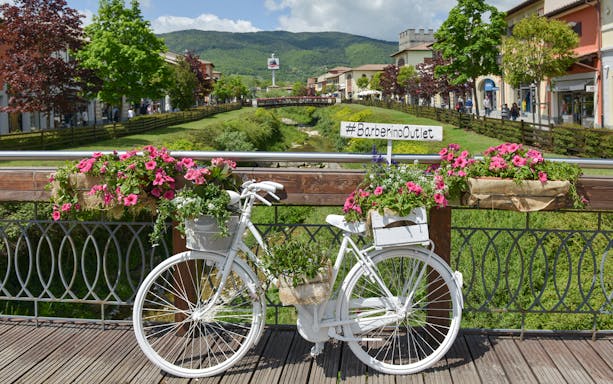 White bicycle with flowers on a bridge at Barberino Designer Outlet, Florence.