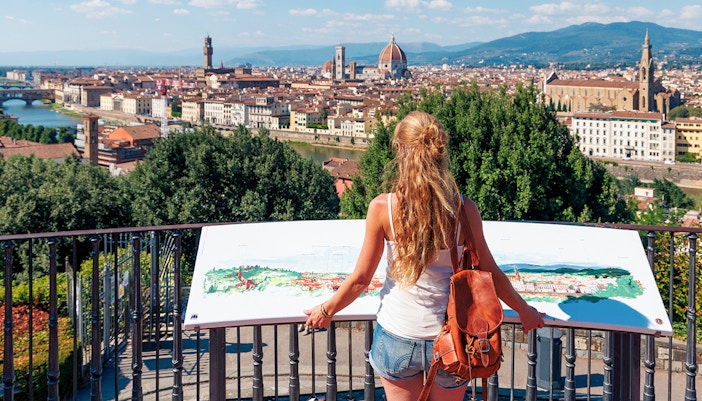 Woman viewing Florence skyline from Piazzale Michelangelo, featuring the Duomo and Palazzo Vecchio.
