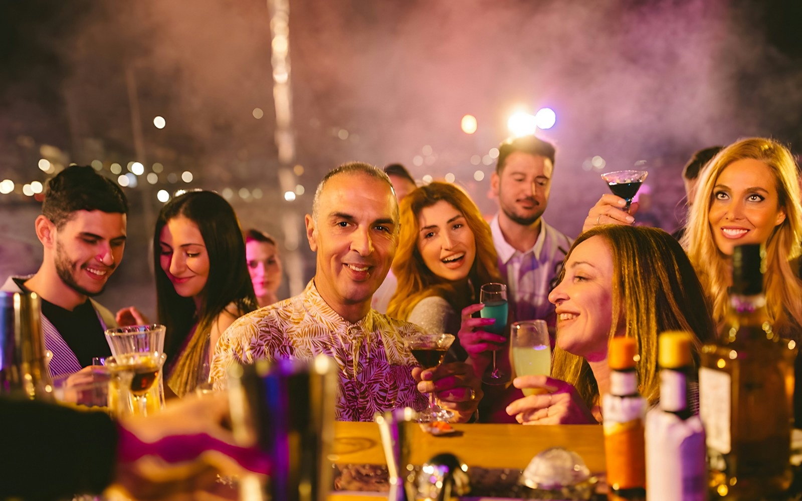 Guests on Athens Riviera Cruise enjoying drinks and live music, Greece coast in background.