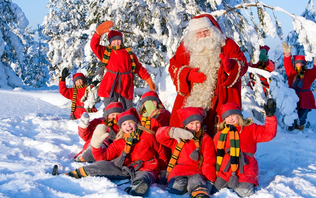 Children with Santa Claus in snowy Santa Claus Village, Rovaniemi.