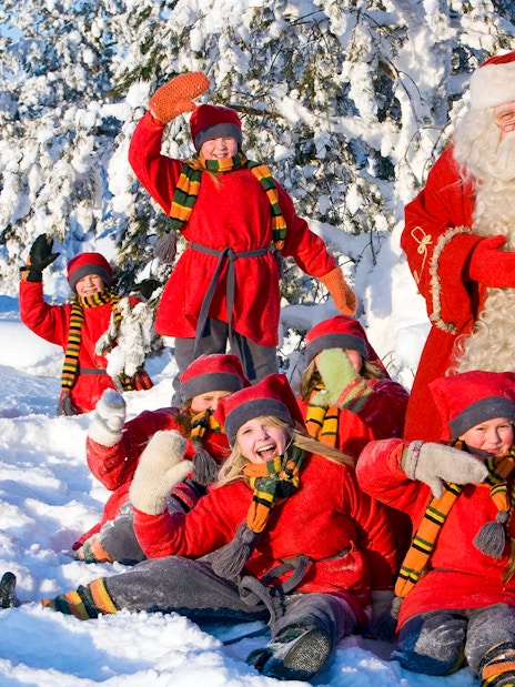 Children with Santa Claus in snowy Santa Claus Village, Rovaniemi.