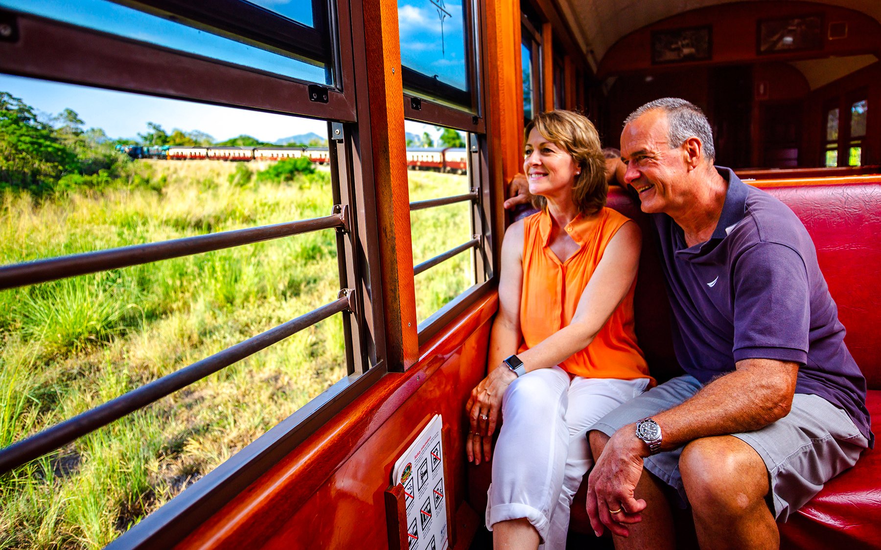 Couple enjoying scenic train ride through Kuranda rainforest near Cairns.