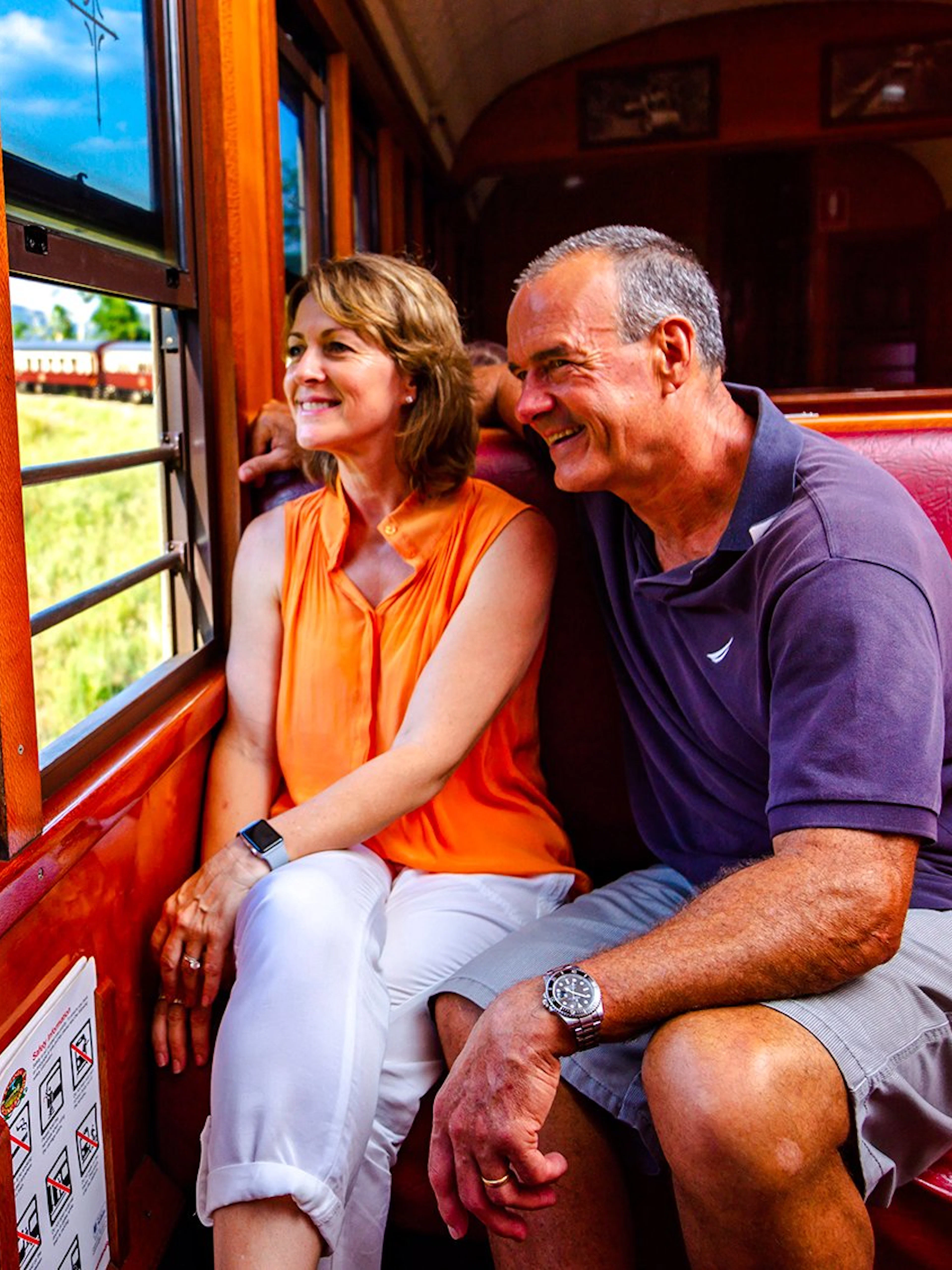 Couple enjoying scenic train ride through Kuranda rainforest near Cairns.