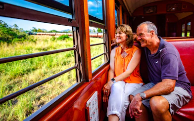 Couple enjoying scenic train ride through Kuranda rainforest near Cairns.