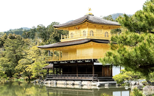 Kinkaku-ji Temple in Kyoto surrounded by trees and reflecting in a pond.
