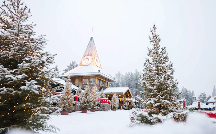 Santa Claus Village in Lapland with snow-covered trees and festive lights.
