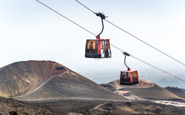 Mount Etna cable car ascending with volcanic crater in the background.