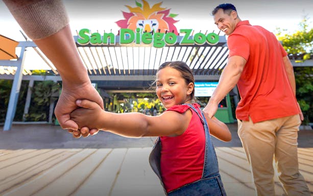 Family entering San Diego Zoo, child smiling and holding hands.