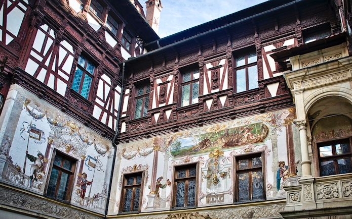 Peles Castle wall details with intricate frescoes and ornate woodwork.