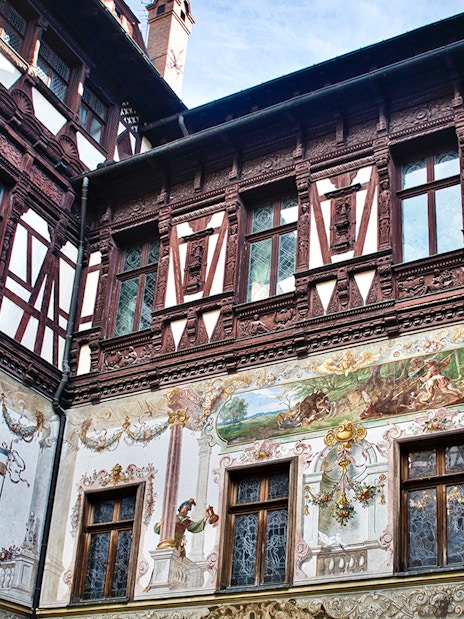 Peles Castle wall details with intricate frescoes and ornate woodwork.