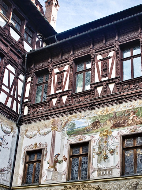 Peles Castle wall details with intricate frescoes and ornate woodwork.