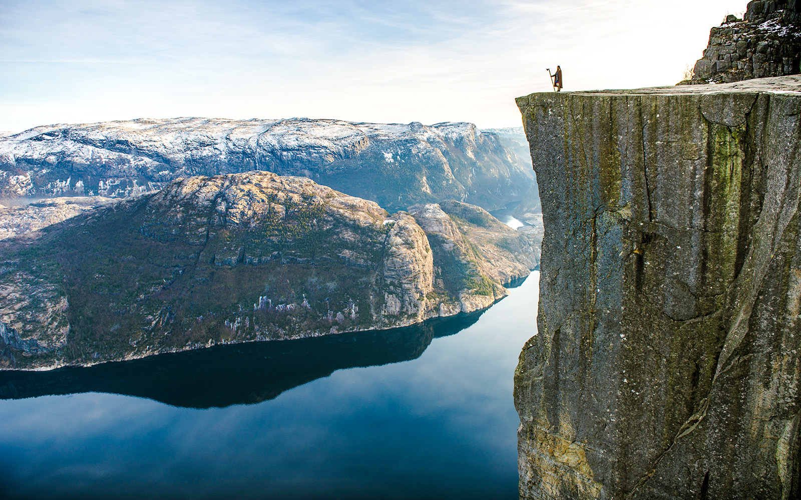 Hiker standing on the edge of Pulpit Rock overlooking Lysefjord, Norway.