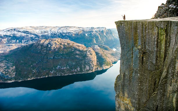 Hiker standing on the edge of Pulpit Rock overlooking Lysefjord, Norway.
