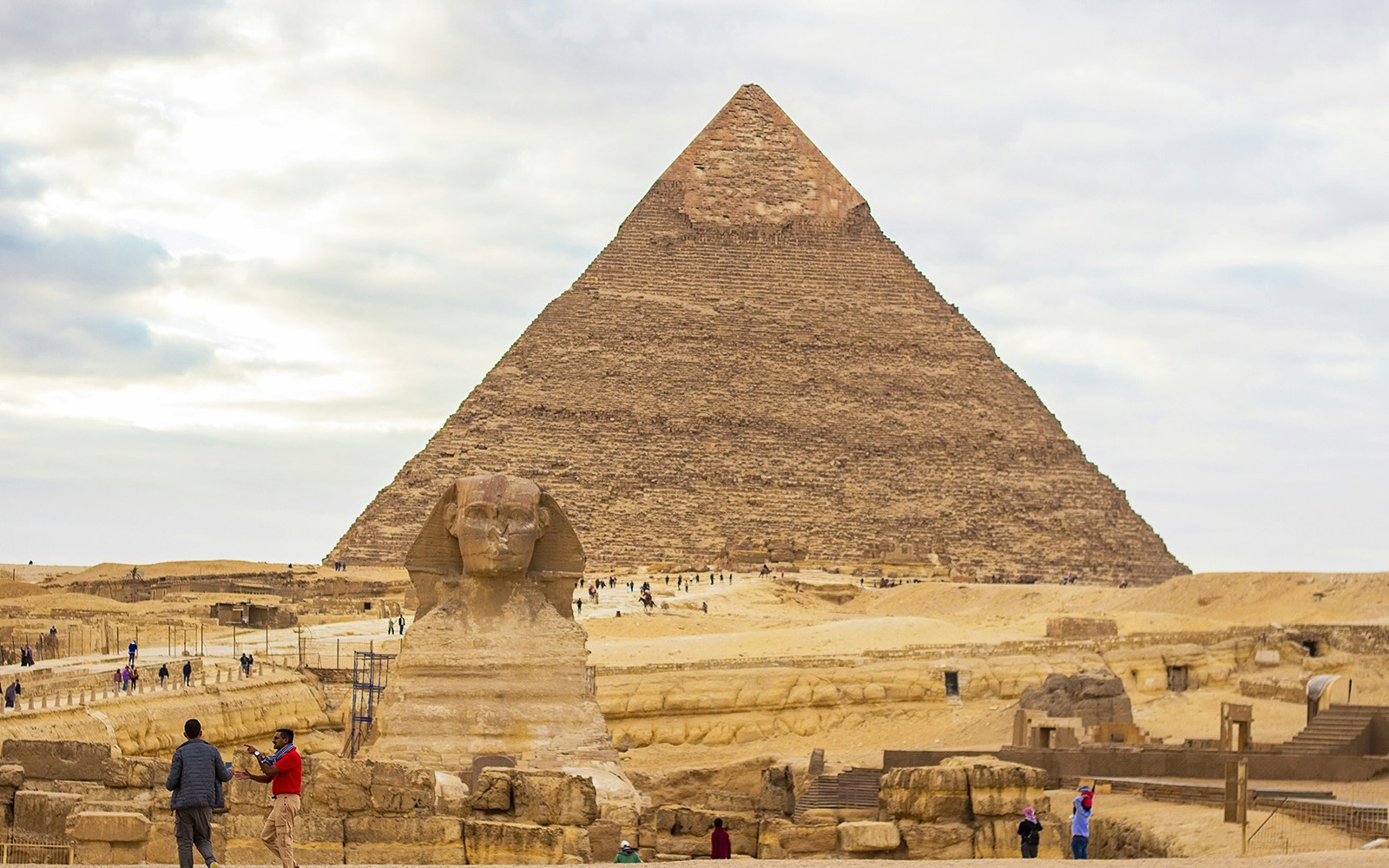 Great Sphinx and Pyramid of Khafre in Giza, Egypt, with tourists exploring the site.