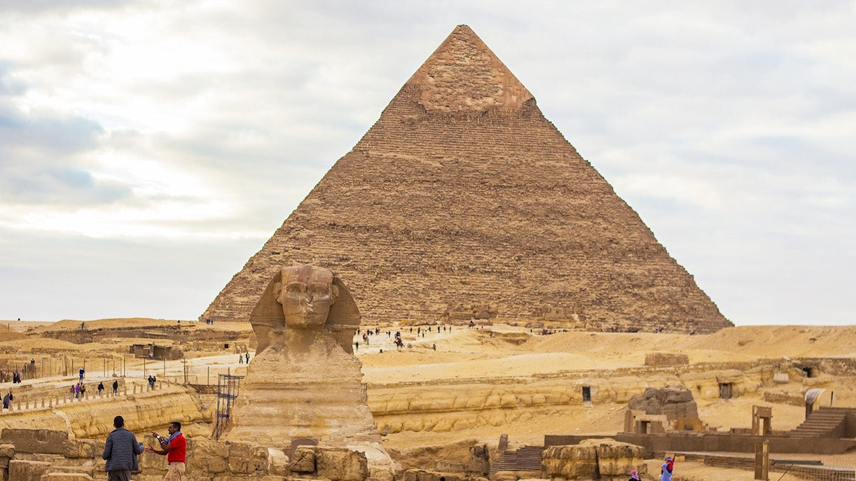 Great Sphinx and Pyramid of Khafre in Giza, Egypt, with tourists exploring the site.