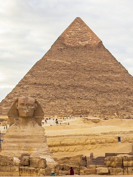 Great Sphinx and Pyramid of Khafre in Giza, Egypt, with tourists exploring the site.