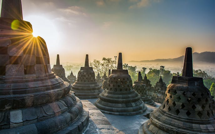 Borobudur stupas at sunrise with misty landscape, Setumbu Hill, Indonesia.