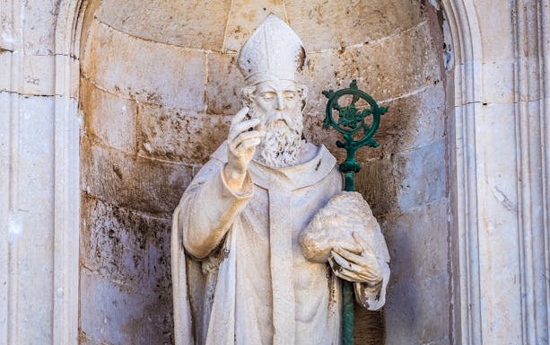 Statue of a bishop holding a staff in Dubrovnik's Old Town.